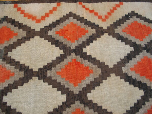 Geometric flatweave rug featuring stepped diamonds outlined in brown and filled with orange and natural beige.