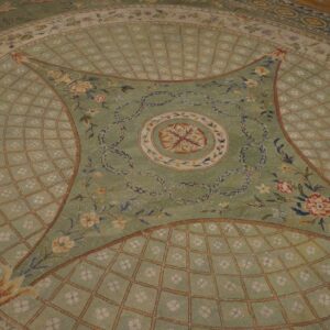 Sage green neoclassical rug with intricate floral designs, decorative garlands, and a pale diamond trellis motif.