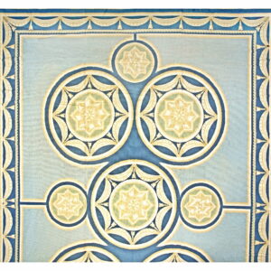 Formal blue rug with interlocking circular star medallions and decorative cream-colored draped borders.