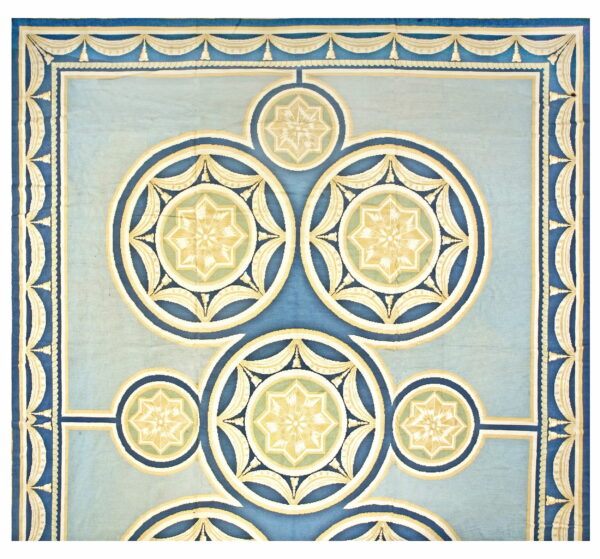Formal blue rug with interlocking circular star medallions and decorative cream-colored draped borders.
