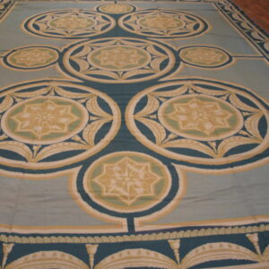 Large low-pile rug featuring teal, gold, and cream geometric star medallions on a pale blue-green field.
