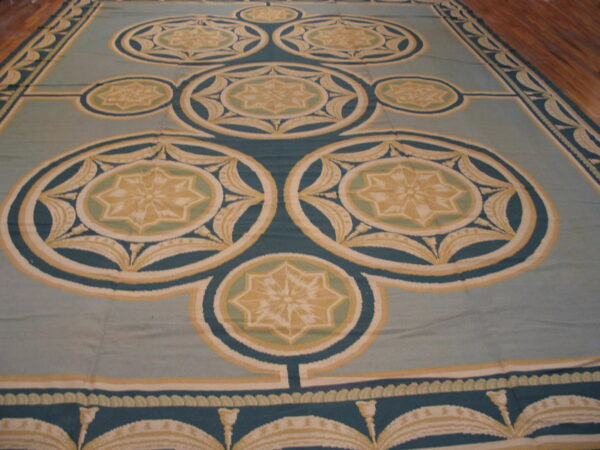 Large low-pile rug featuring teal, gold, and cream geometric star medallions on a pale blue-green field.