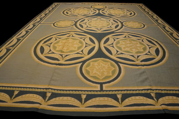 Flatwoven rug featuring large geometric star medallions in teal, gold, and sage green colors.