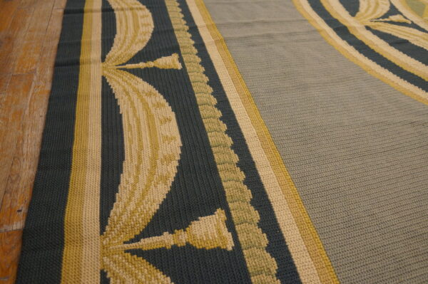 A flat, textured rug featuring teal, pale yellow, and sage botanical patterns rests on hardwood flooring.