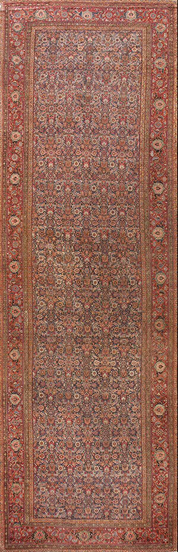 Narrow runner rug with a dense navy field pattern and a wide, intricate red and rust primary border.