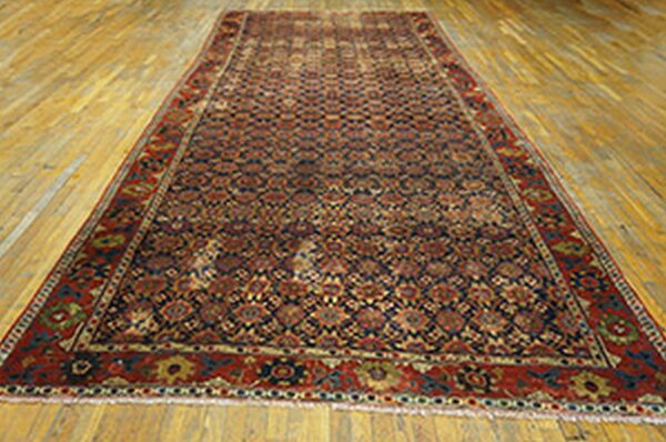 Traditional red and navy runner rug with complex geometric patterns displayed on light wood plank flooring.