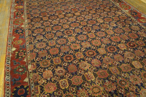 Navy rug with repeating geometric floral motifs in rust, gold, and green on light wood flooring.