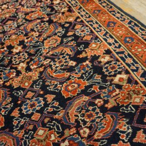 Navy rug featuring intricate repeating patterns in terracotta, light blue, and beige, displayed on wood floors.