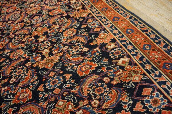 Navy rug featuring intricate repeating patterns in terracotta, light blue, and beige, displayed on wood floors.