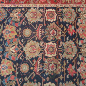 Navy rug detail showing a dense pattern of multi-colored floral and geometric motifs bordered by red.