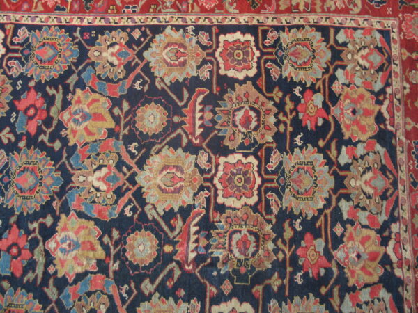 Navy rug detail showing a dense pattern of multi-colored floral and geometric motifs bordered by red.