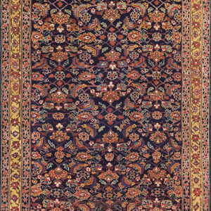 Dark blue rug covered in intricate red, orange, and yellow floral designs with a wide patterned gold border.