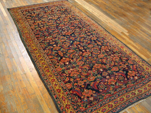 Long runner with navy and red floral pattern and yellow borders rests on light wood flooring.