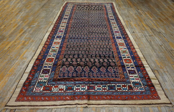 A dark blue runner rug with intricate patterns and multi-colored borders lies on worn wood flooring.