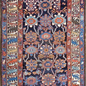 Navy rug with repeating medallions in blue and rust, framed by borders depicting geometric animals on ivory.