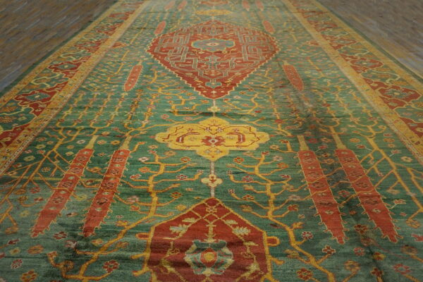 Ornate teal rug featuring rust red medallions and intricate yellow tree patterns on dark wood flooring.