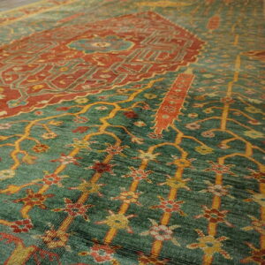 Ornate traditional rug with a central rust medallion and yellow floral motifs on a textured sage green field.