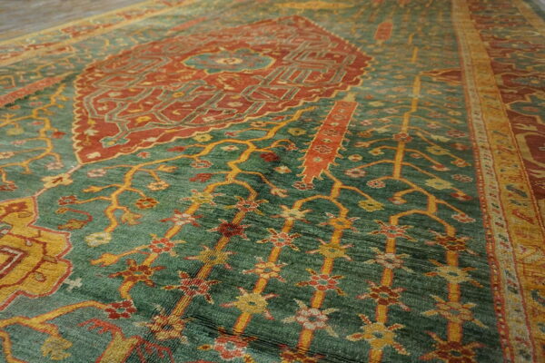 Ornate traditional rug with a central rust medallion and yellow floral motifs on a textured sage green field.