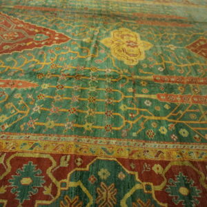 Traditional green and rust rug featuring intricate yellow vines and a detailed central medallion.