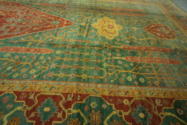 Traditional green and rust rug featuring intricate yellow vines and a detailed central medallion.