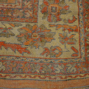 Textured area rug featuring geometric and floral patterns in muted gold, rust, and slate gray.