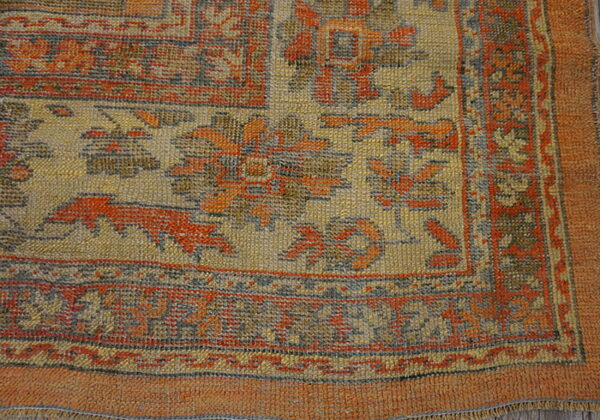 Textured area rug featuring geometric and floral patterns in muted gold, rust, and slate gray.