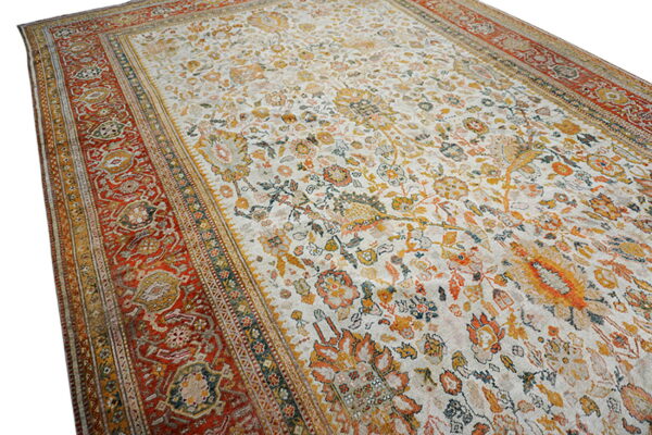 Low-pile rug with a cream field, orange and yellow faded floral patterns, and a thick red border.