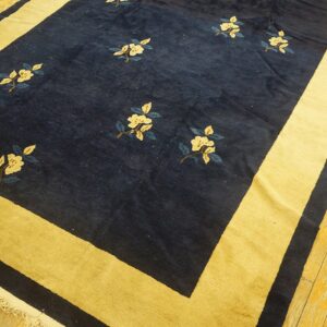 Navy blue rug with scattered cream floral motifs and a wide mustard yellow border on wood planks.