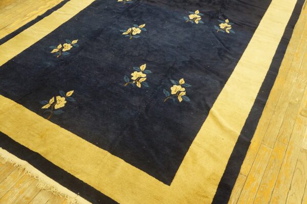 Navy blue rug with scattered cream floral motifs and a wide mustard yellow border on wood planks.