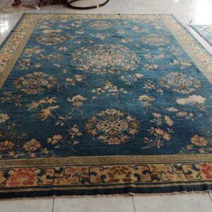 Ornate deep blue rug featuring tan and salmon floral patterns and circular medallions on tile flooring.