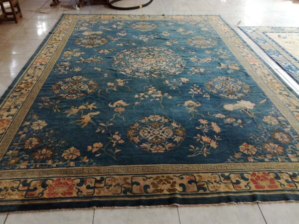 Ornate deep blue rug featuring tan and salmon floral patterns and circular medallions on tile flooring.
