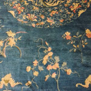 Detail view of a navy blue rug with scattered peach and yellow flowering vine motifs.