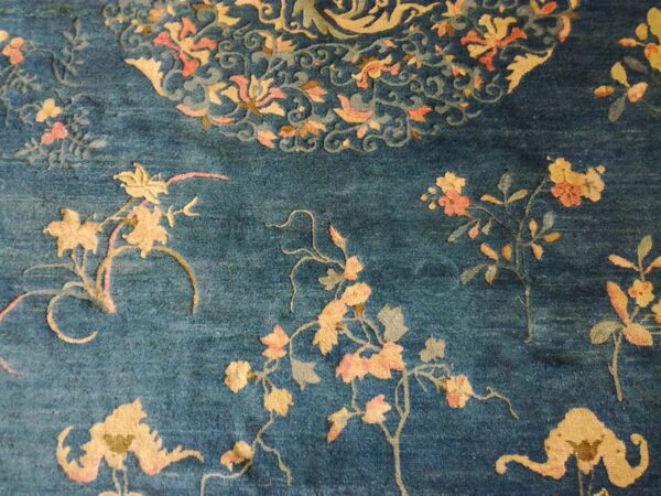 Detail view of a navy blue rug with scattered peach and yellow flowering vine motifs.