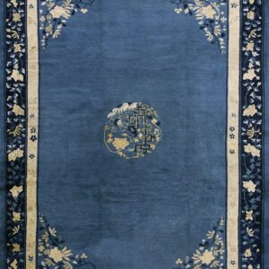 Rectangular blue rug with a central round medallion and elaborate gold and indigo floral borders.