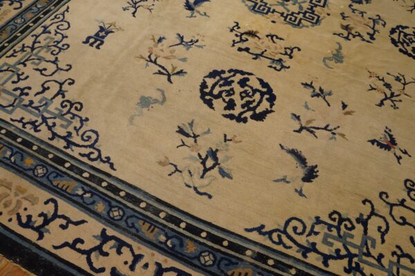 Light beige rug with scattered blue floral motifs and a complex dark blue and teal patterned border.