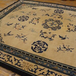 Beige rug with navy and light blue border patterns, scattered medallions, and florals on wood floor.