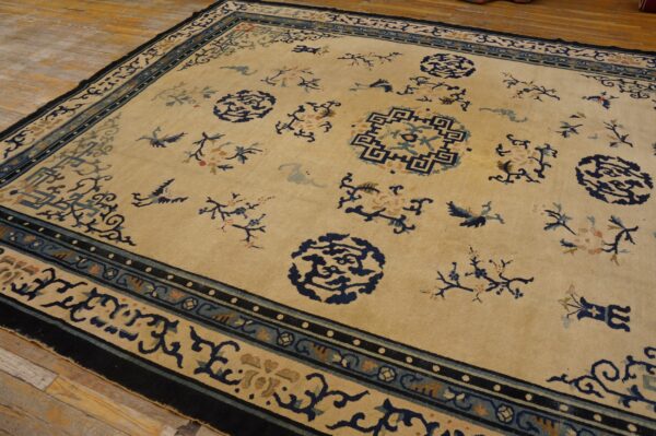 Beige rug with navy and light blue border patterns, scattered medallions, and florals on wood floor.
