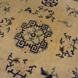 Low-pile tan rug detailed with dark blue geometric medallions and stylized blue and brown floral motifs.
