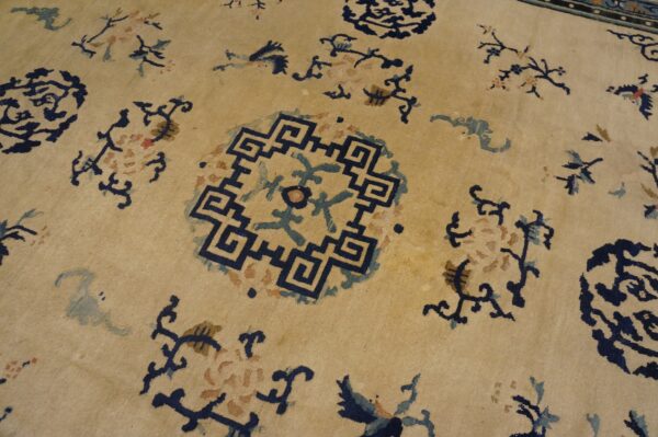 Low-pile tan rug detailed with dark blue geometric medallions and stylized blue and brown floral motifs.