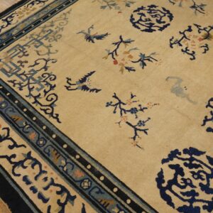 Beige rug featuring navy, teal, and tan scattered medallions, birds, and complex borders on wood floor.