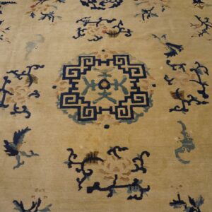 Low-pile rug with a cream field, navy geometric center, and scattered blue, teal, and pink floral designs.