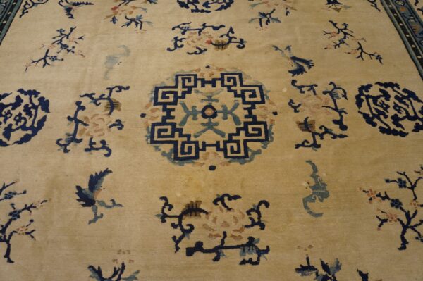 Low-pile rug with a cream field, navy geometric center, and scattered blue, teal, and pink floral designs.