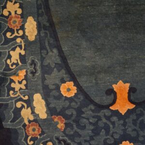 Teal and navy rug border featuring stylized tan and orange flowers rests beside light golden hardwood floorboards.