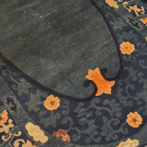 High-pile indigo and teal rug featuring stylized orange, tan, and brown floral motifs.