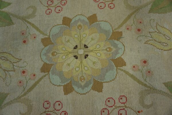 Muted floral rug detail showing a stylized yellow medallion, tan leaves, and pink berries on a beige ground.