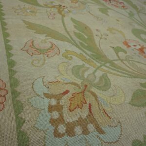 Muted flatweave rug featuring a large-scale botanical pattern with a beige ground and pastel floral accents.