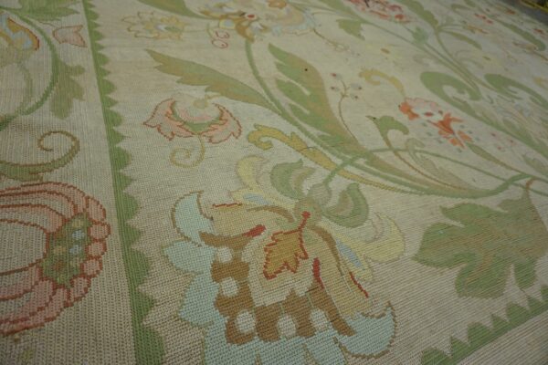 Muted flatweave rug featuring a large-scale botanical pattern with a beige ground and pastel floral accents.