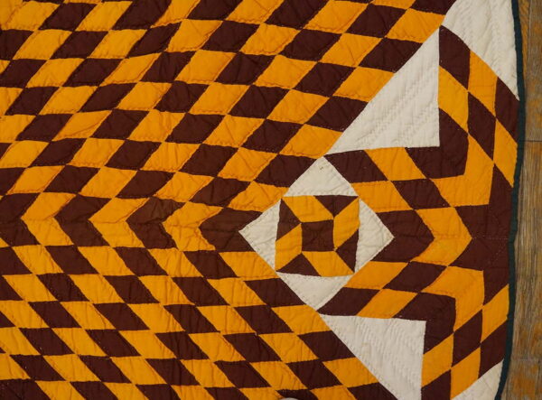 Low-pile quilted textile featuring a brown, gold, and white radiating geometric diamond pattern.