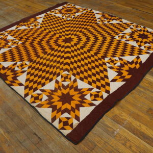 Brown, gold, and white geometric star pattern textile rests flatly on distressed wood plank flooring.