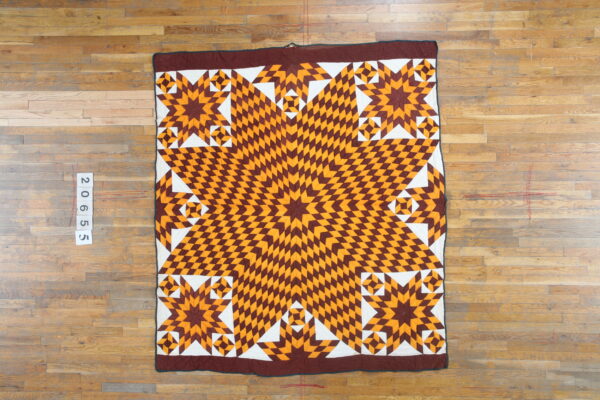 Low-profile textile with a geometric brown, orange, and white star pattern on wood flooring.